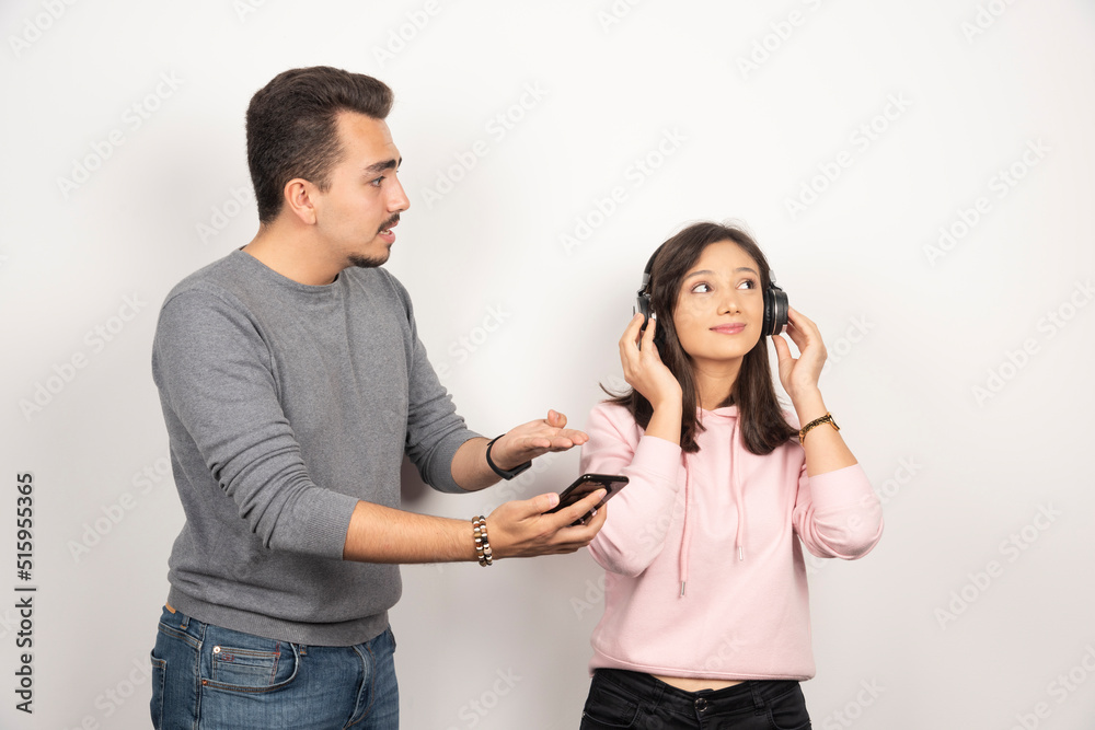Young man trying to get reach out woman for looking at his phone Young man trying to get reach out woman for looking at his phone