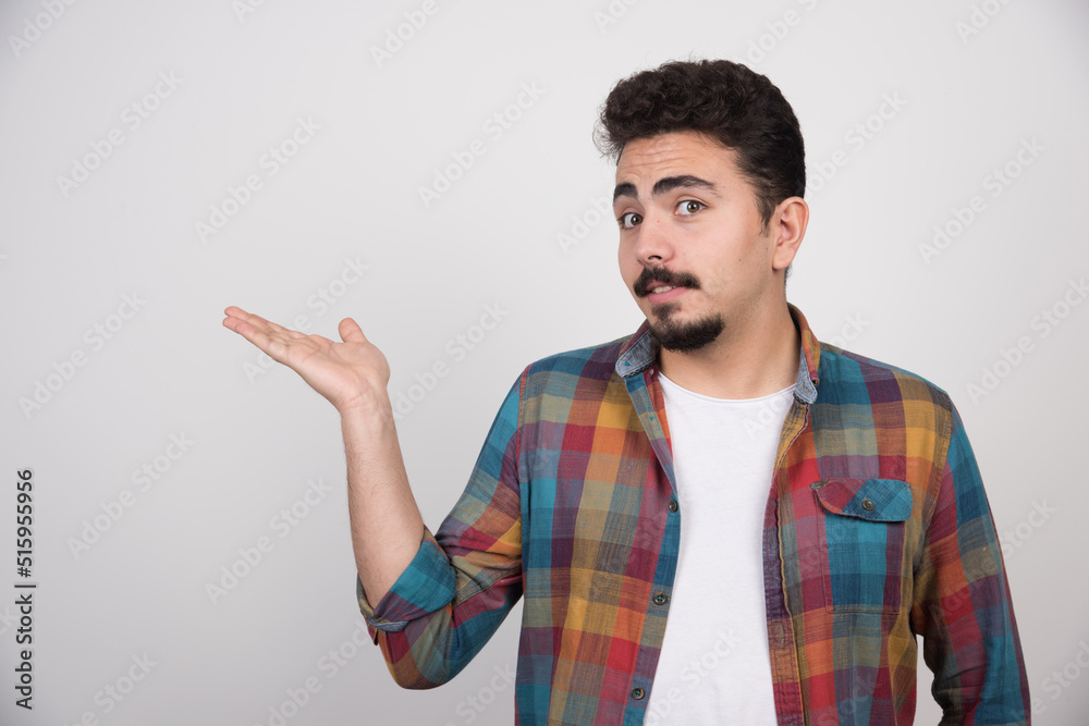 A handsome man pointing with one hand inviting someone A handsome man pointing with one hand inviting someone