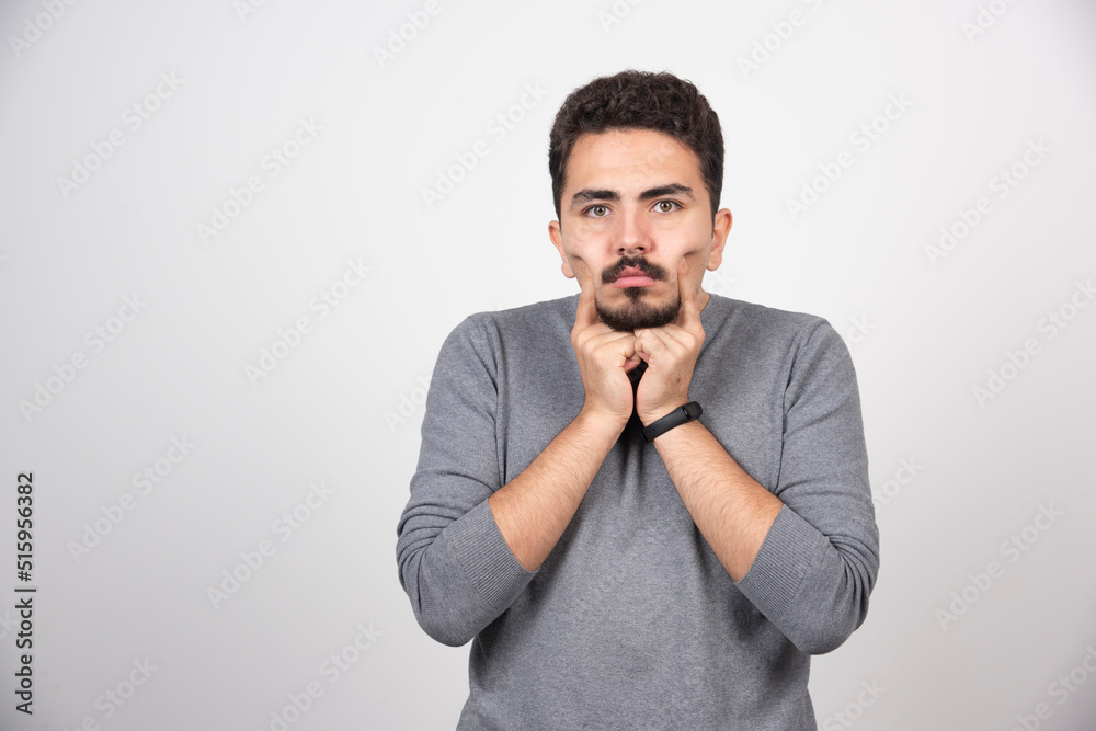 A young man posing with hands over a white wall A young man posing with hands over a white wall