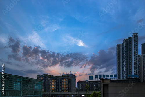 In the evening, the blue sky has a fire cloud-like evening sunset, and the afterglow of the sunset shines on the sky, which is very beautiful. Under the sky are the buildings of the city