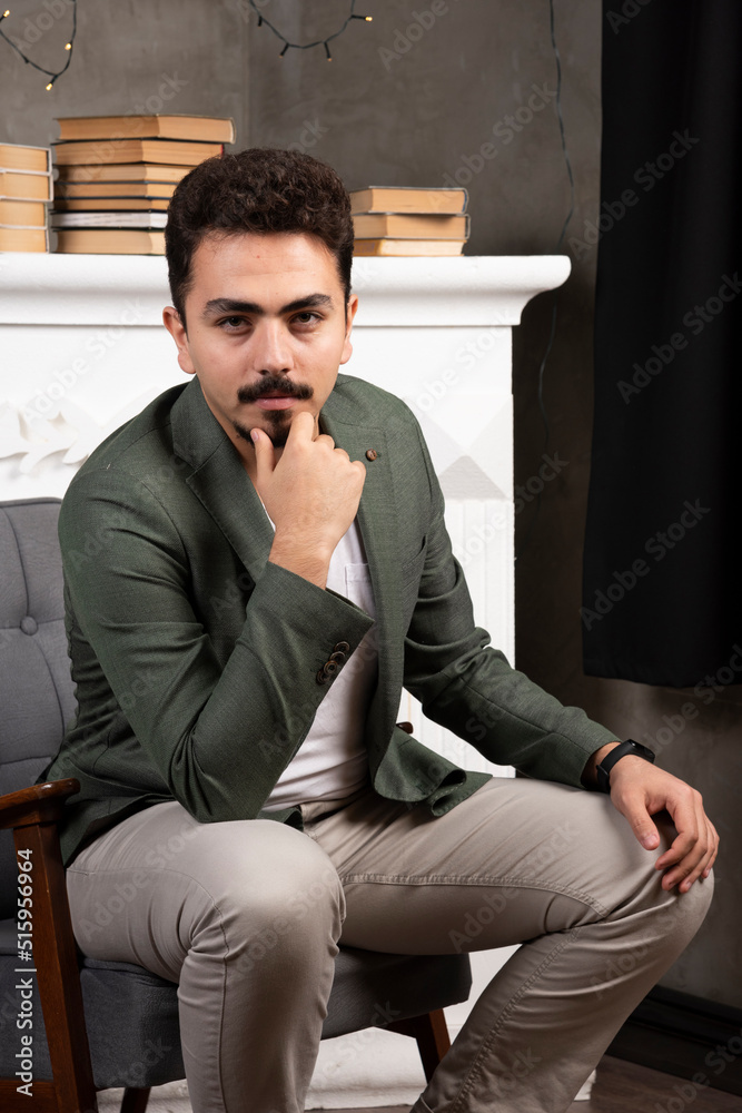 Young handsome man looking confident at the camera smiling with crossed arms and hand raised on chin.