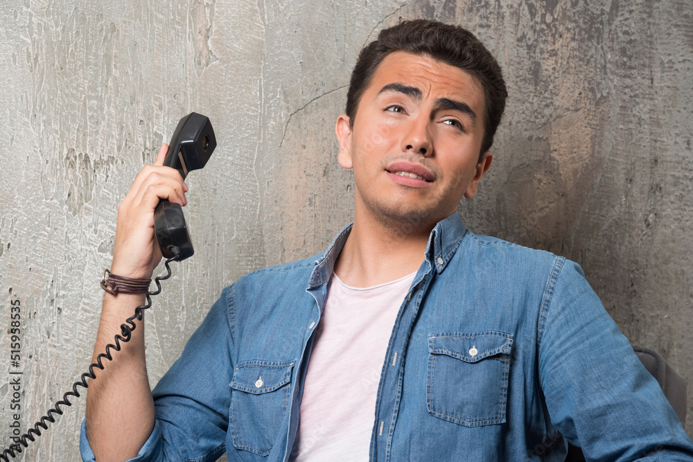 Naklejka premium Photo of young man talking on phone and sitting on chair