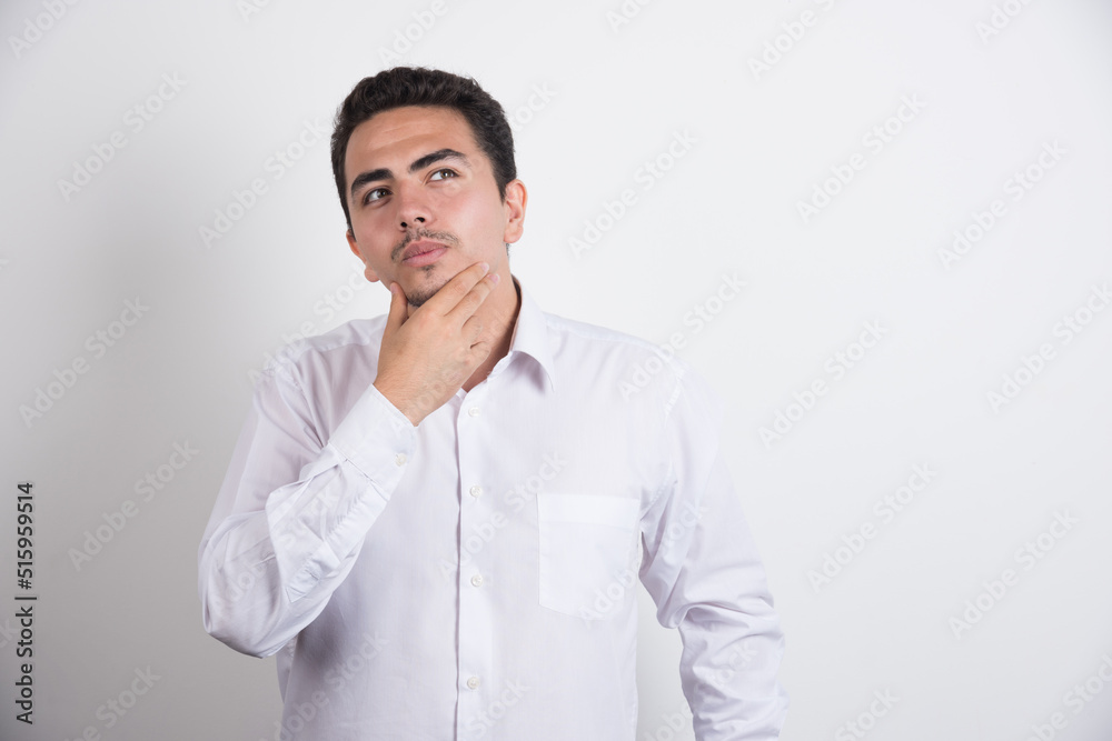 Young businessman holding his chin on white background Young businessman holding his chin on white background