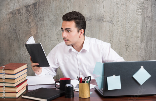 Obraz na plátne Young businessman looking closely at notebook at the desk