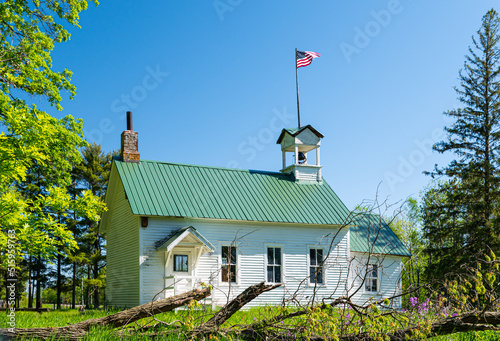1900's one room school house with American flag and bell tower in rural Minnesota. 