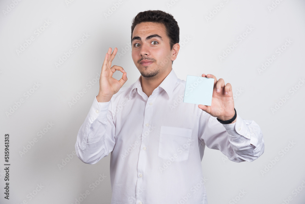 Businessman holding memo pads and showing ok sign on white background Businessman holding memo pads and showing ok sign on white background