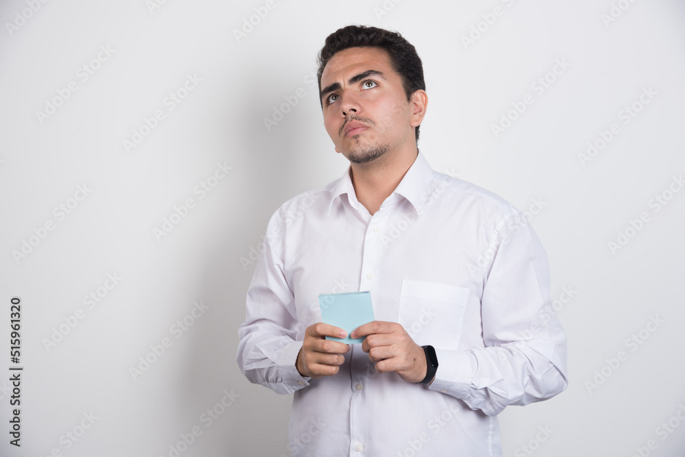 Serious businessman with memo pads looking up on white background Serious businessman with memo pads looking up on white background