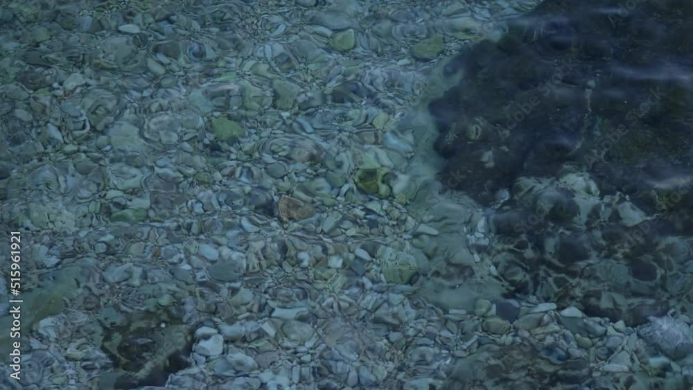 Slight roughness on surface of water. Seabed stones is visible through crystal clear water. Limestone on the shore. Light storm and waves on the surface of the water. Rovinj, Croatia - Circa 2022, May Slight roughness on surface of water. Seabed stones is visible through crystal clear water. Limestone on the shore. Light storm and waves on the surface of the water. Rovinj, Croatia - Circa 2022, May