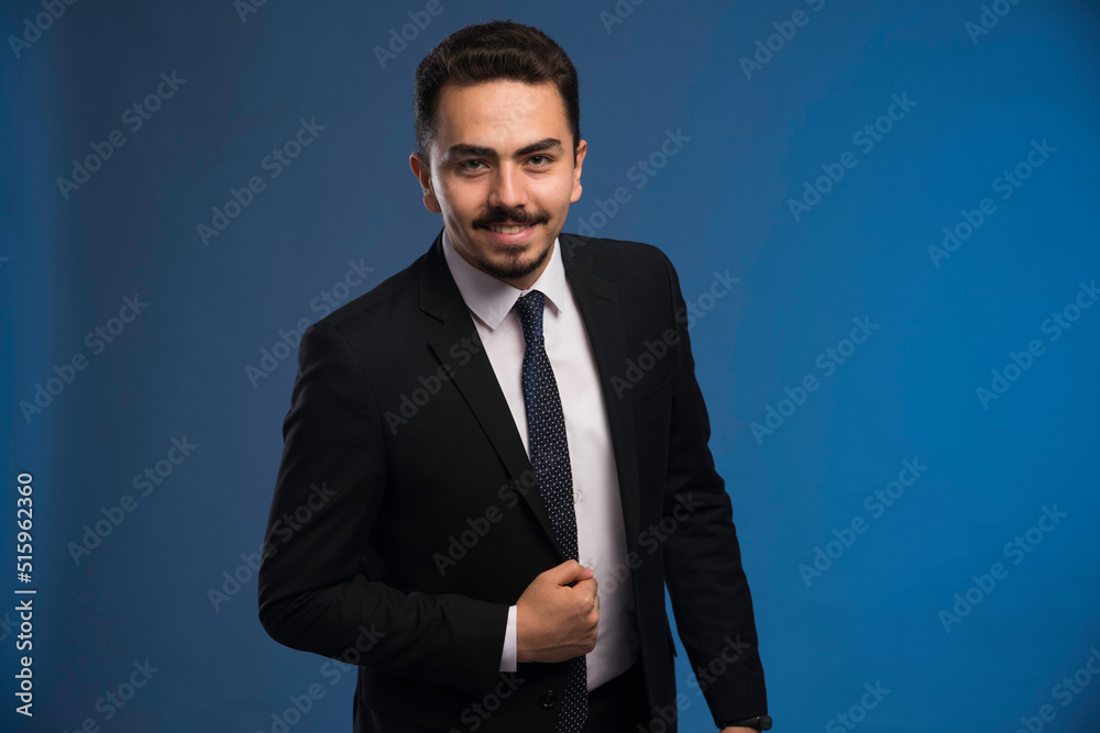 Businessman in black suit with a tie posing positive Businessman in black suit with a tie posing positive