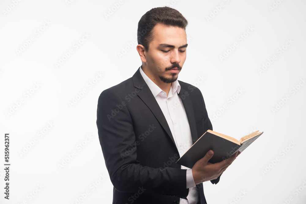 Businessman in black suit holding his tasklist and checking it Businessman in black suit holding his tasklist and checking it
