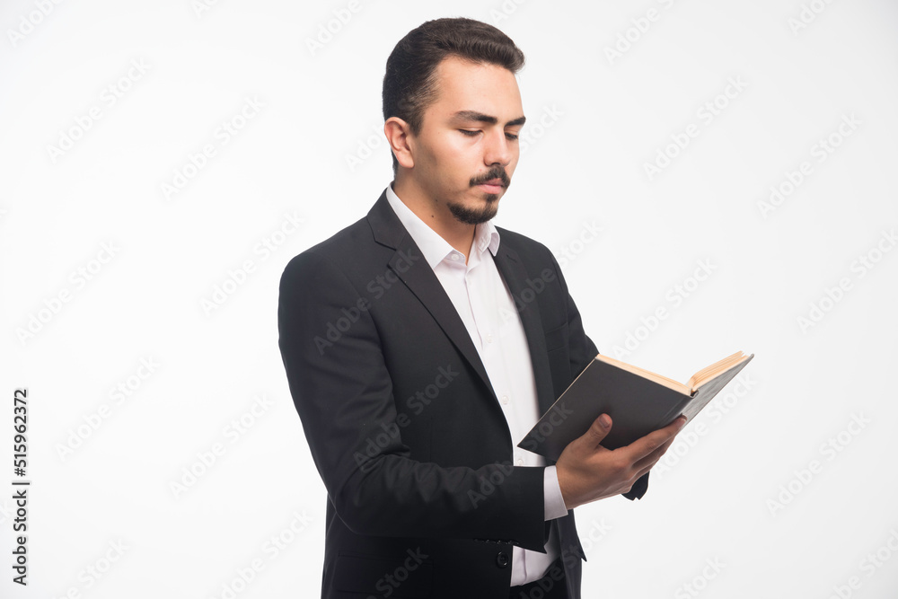 Businessman in black suit holding his tasklist and checking it Businessman in black suit holding his tasklist and checking it