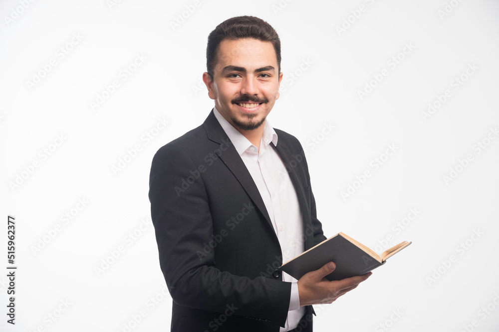 Businessman in black suit holding his tasklist and smiling Businessman in black suit holding his tasklist and smiling