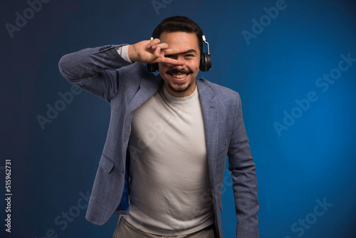 Male dj in grey suit listening to headphones and dancing