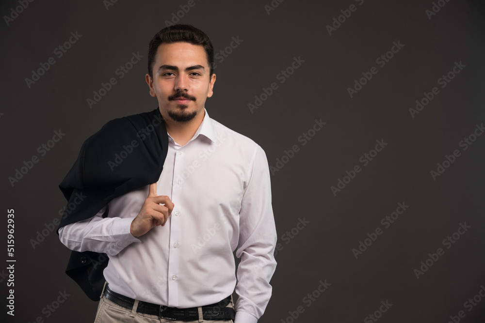 A businessman in dress code holding a black jacket in his shoulder