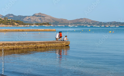 Fototapeta Naklejka Na Ścianę i Meble -  The beach and promenade with the piers of Port de Pollença in the evening at sunset.