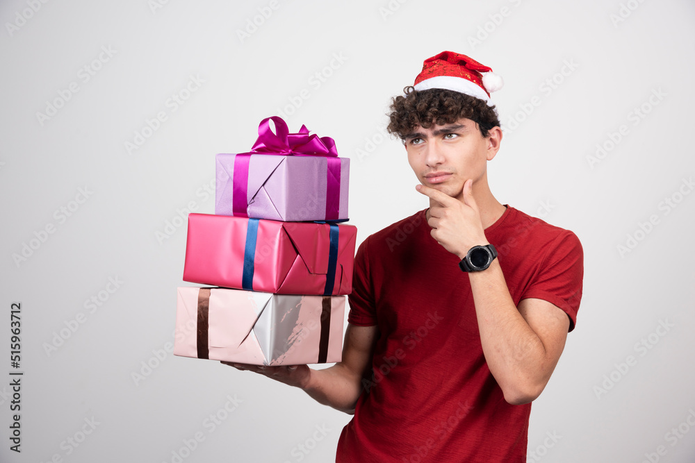 Young man with gift boxes thinking about something Young man with gift boxes thinking about something