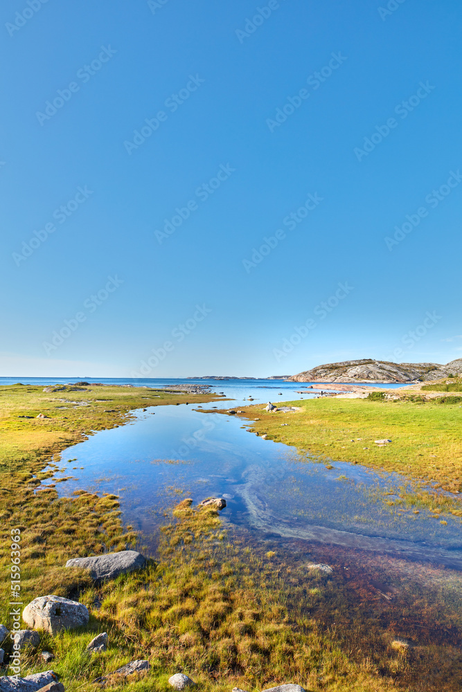 Scenic view of a river flowing through a swamp and leading to the ocean in Norway. Landscape view of blue copy space sky and a marshland. Overflow of water pollution and oil deposits entering the sea