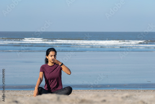 Woman doing yoga Anulom Vilom, breathing on beach. Jogging, workout, exercise, healthy life, diet, lifestyle, sedentary, active, fresh, fitness, periods, sunlight, muscle, work life balance concept.
