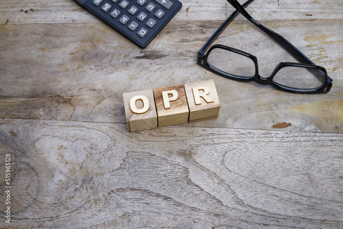 The word OPR on the wooden blocks with a calculator, and eyeglasses at the back
