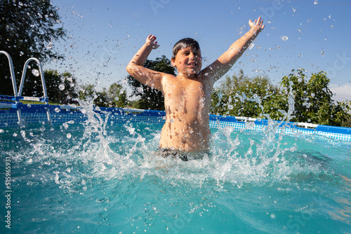 boy jumping and squirting in the pool on a sunny summer day