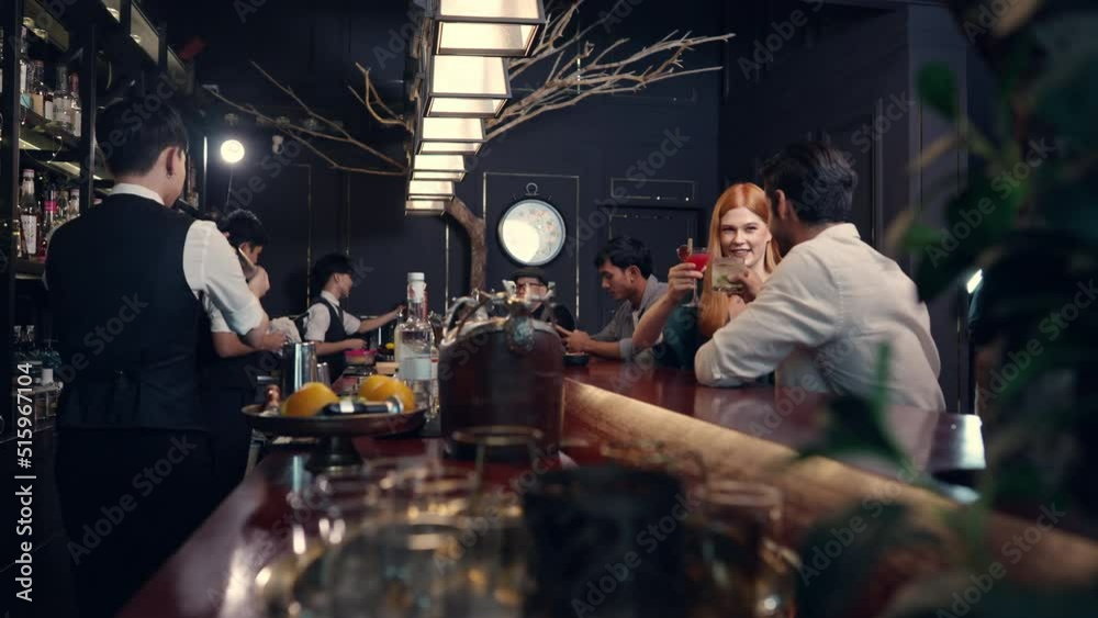 4K Group of People man and woman enjoy hangout nightlife celebrating party drinking cocktail beverage at luxury bar. Bartender preparing alcoholic drink serving customer on bar counter at nightclub