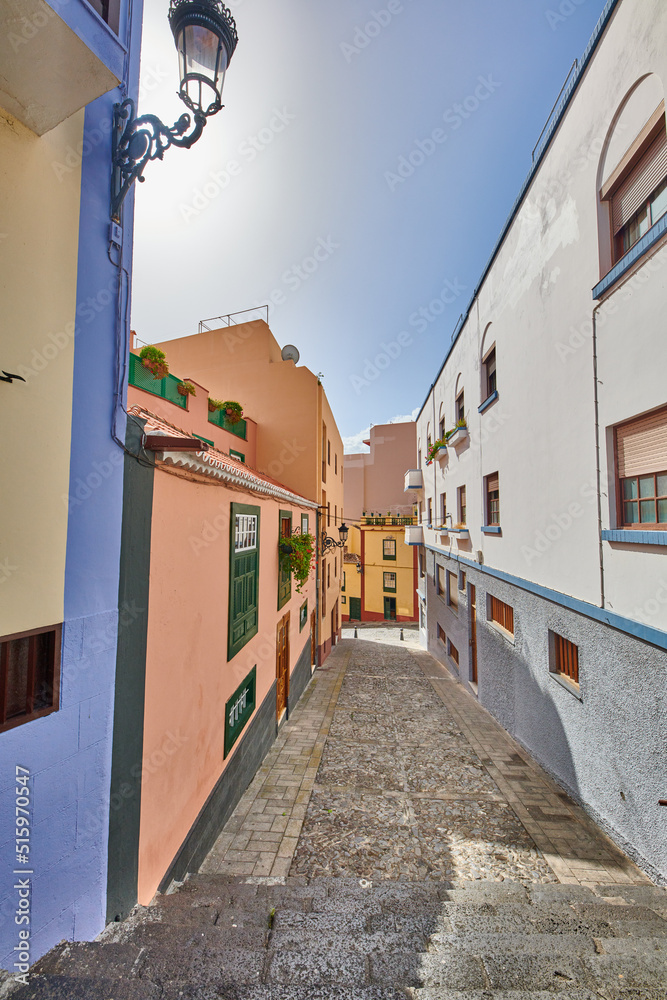 Narrow street with colorful houses and a blue sky. Architecture of tiny walk way between old townhouse buildings. Empty lane in a beautiful city for exploring and sightseeing, Santa Cruz de La Palma