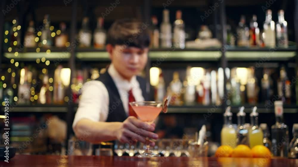 4K Professional male bartender preparing and serving cocktail drink to customer on bar counter at luxury nightclub. Barman making mixed alcoholic drink for celebrating holiday party at restaurant bar. 4K Professional male bartender preparing and serving cocktail drink to customer on bar counter at luxury nightclub. Barman making mixed alcoholic drink for celebrating holiday party at restaurant bar.