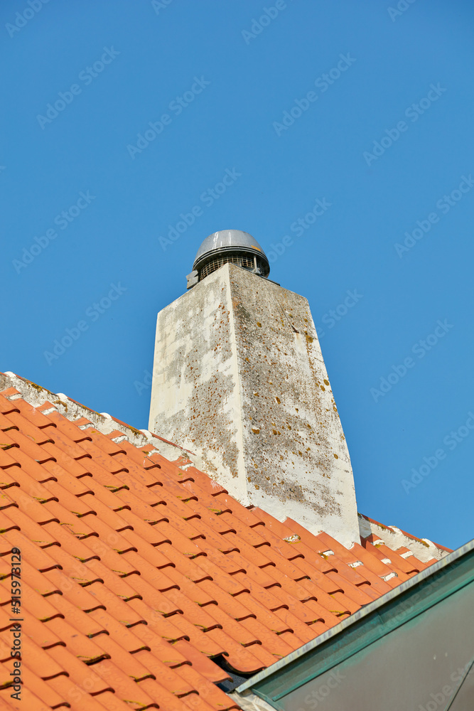 Concrete chimney designed on slate house roof or building outside against clear blue sky background, copyspace. Construction of exterior escape chute built on rooftop for fireplace smoke and heat