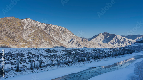 An ice-free river between icy shores. Melted ice floes on turquoise water. Reflection. A picturesque mountain range against a clear blue sky. Altai. Katun © Вера 