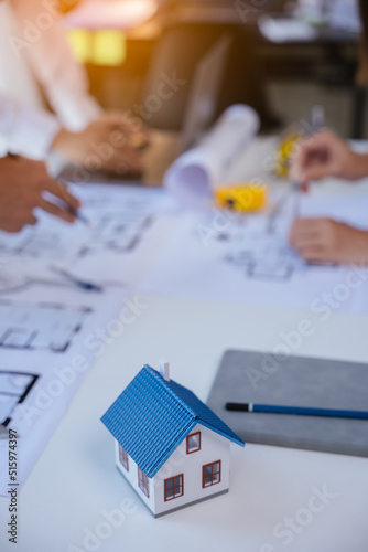 Close up of hands working and brainstorming on paperworks and floor plan drawings about design architectural and engineering for houses and buildings. focus on house model.