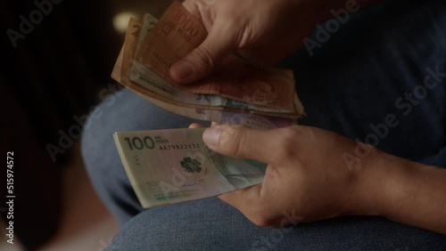 Colombian saver is accounting his savings in a full collection of colombian pesos bills and exchange them for one bill of one hundred us dollar to protect his finances against inflation photo