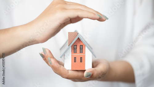 Hands of a woman surround a house model