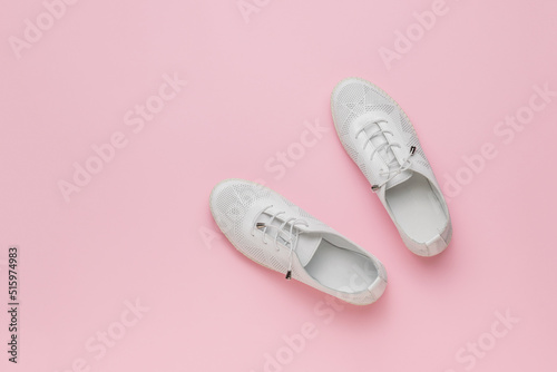 Sporty white shoes on a pink background. Minimal concept of beauty and sports.