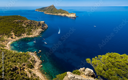 Panorama view from a cliff of the rocky coastline of idyllic Mallorca cove Cala en Basset nearby Sant Elm with boats and the island Sa Dragonera with the mountain Puig des Aucells in the background.