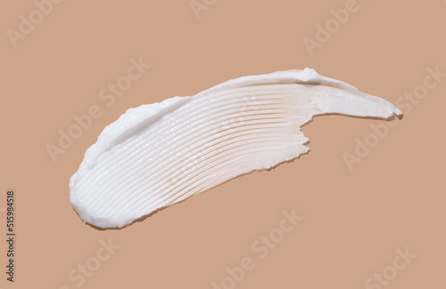 White cosmetic cream lotion swatch smear smudge on brown color background. 