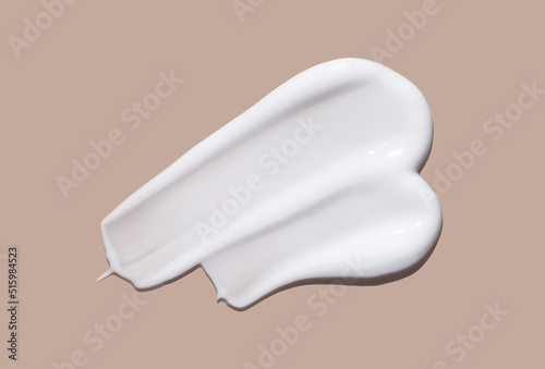 White cosmetic cream lotion swatch smear smudge on brown color background. 