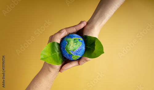 Fototapeta Naklejka Na Ścianę i Meble -  World Earth Day Concept. Green Energy, ESG, Renewable and Sustainable Resources. Environmental and Ecology Care. Hands of People  Embracing Green Leaf and Handmade Globe
