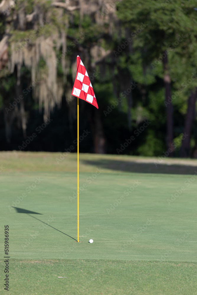 Obraz premium Golf ball near a flagstick on a golf course.