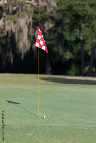 Golf ball near a flagstick on a golf course.