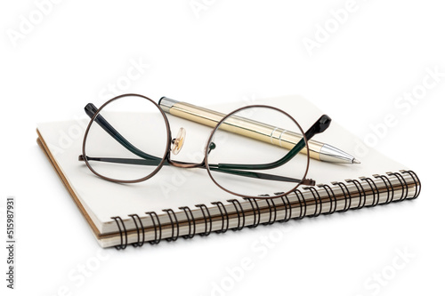 Eyeglasses with pen on the notepad. Isolated on white.