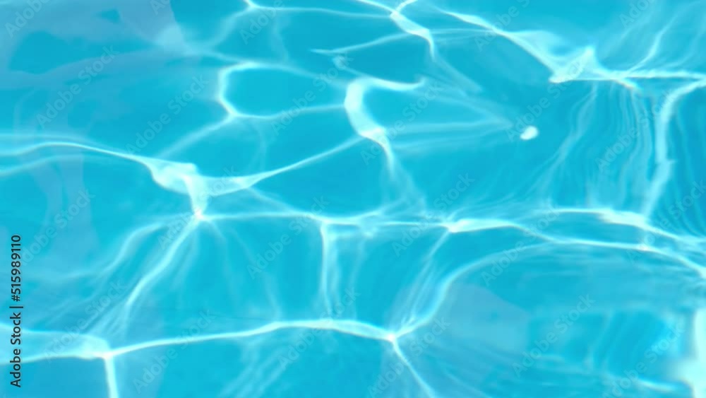 Background of pure light blue water in swimming pool with sun reflections. Rippled water surface in pool