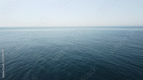 Abstract aerial sea summer ocean sunset nature background. Seagulls are flying over calm water surface in motion blur with golden bokeh lights from sun. Holiday, vacation and recreational concept.