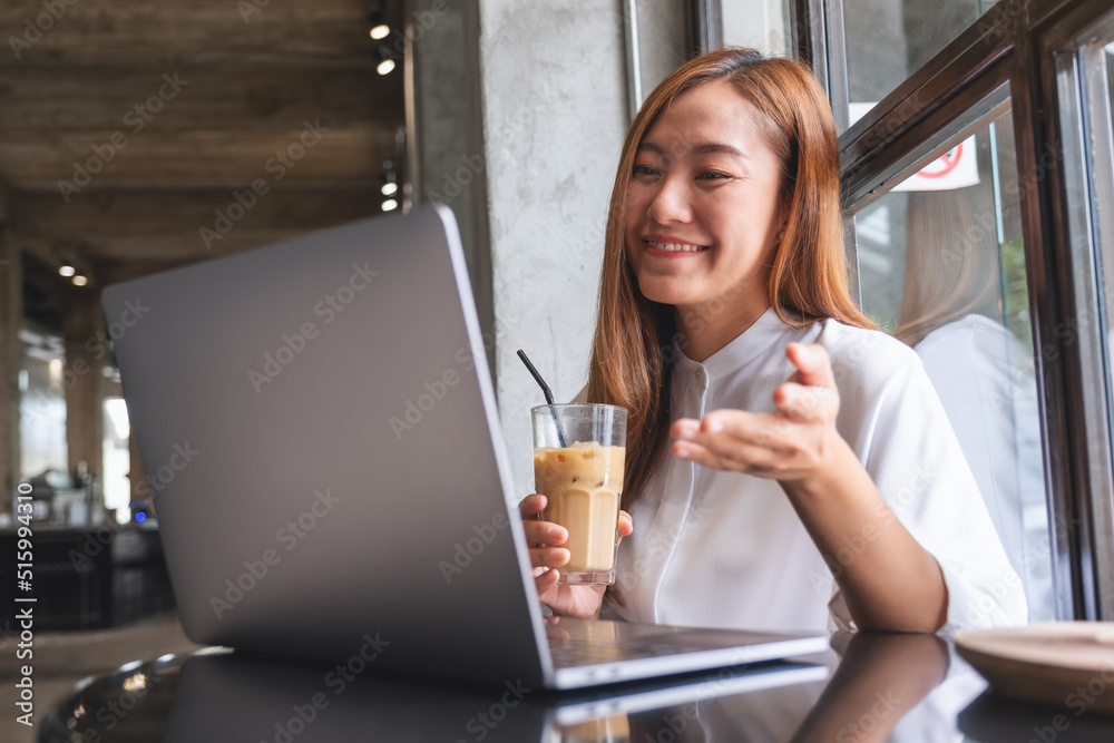 A beautiful young asian woman using laptop computer for video call, online meeting while drinking coffee A beautiful young asian woman using laptop computer for video call, online meeting while drinking coffee