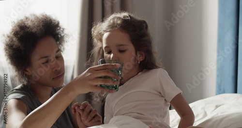 Mom giving water to sick daughter