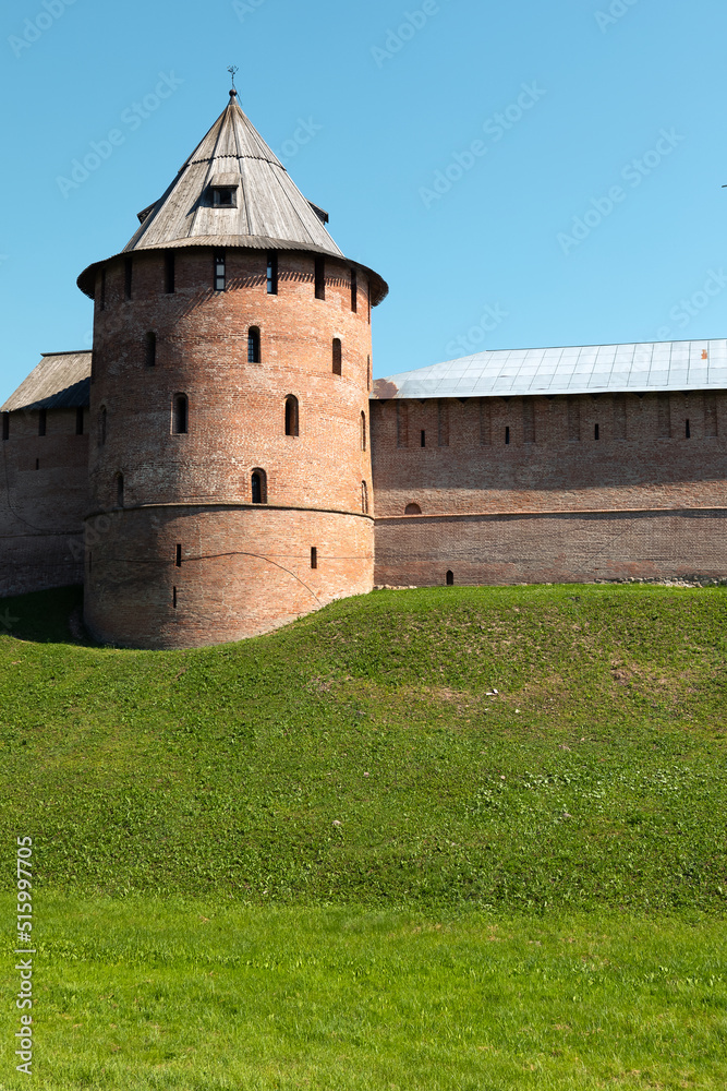 The Tower of Kremlin in Velikiy Novgorod. Meadow in front of ancient wall and tower.