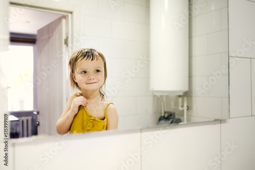 Cute toddler baby combs in front of bathroom mirror