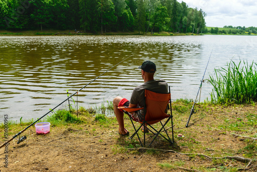 photo from summer with an angler, angler sits on the shore of the lake and catches fish,