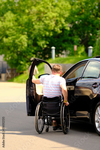 a person on the wheelchair holds his hand on the car door, driver with disability
