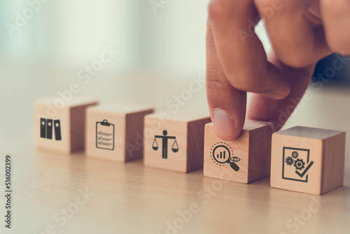 Audit business concept. Examination and evaluation of the financial statements of an organization; income statement, balance sheet, cash flow statement.  Holding wooden cubes with audit icon. photo