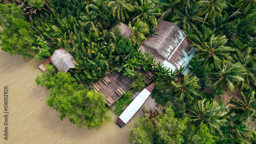 aerial top down view of local home along tropical jungle of mekong river in Ben Tre Vietnam with dock and boat